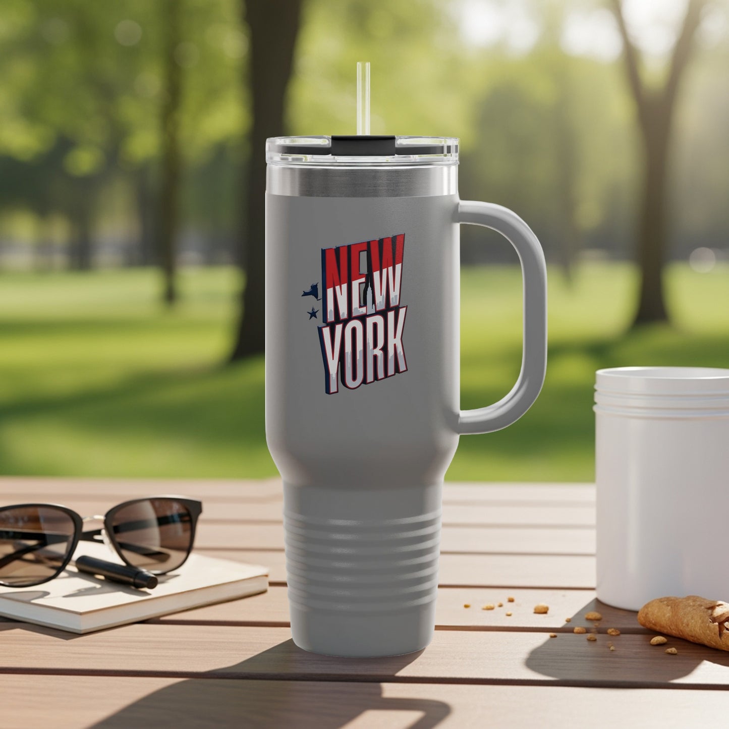 Gray travel mug with "New York" text and stars, on a table.