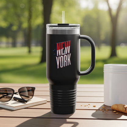 Black travel mug with "NEW YORK" text and graphic, outdoors.