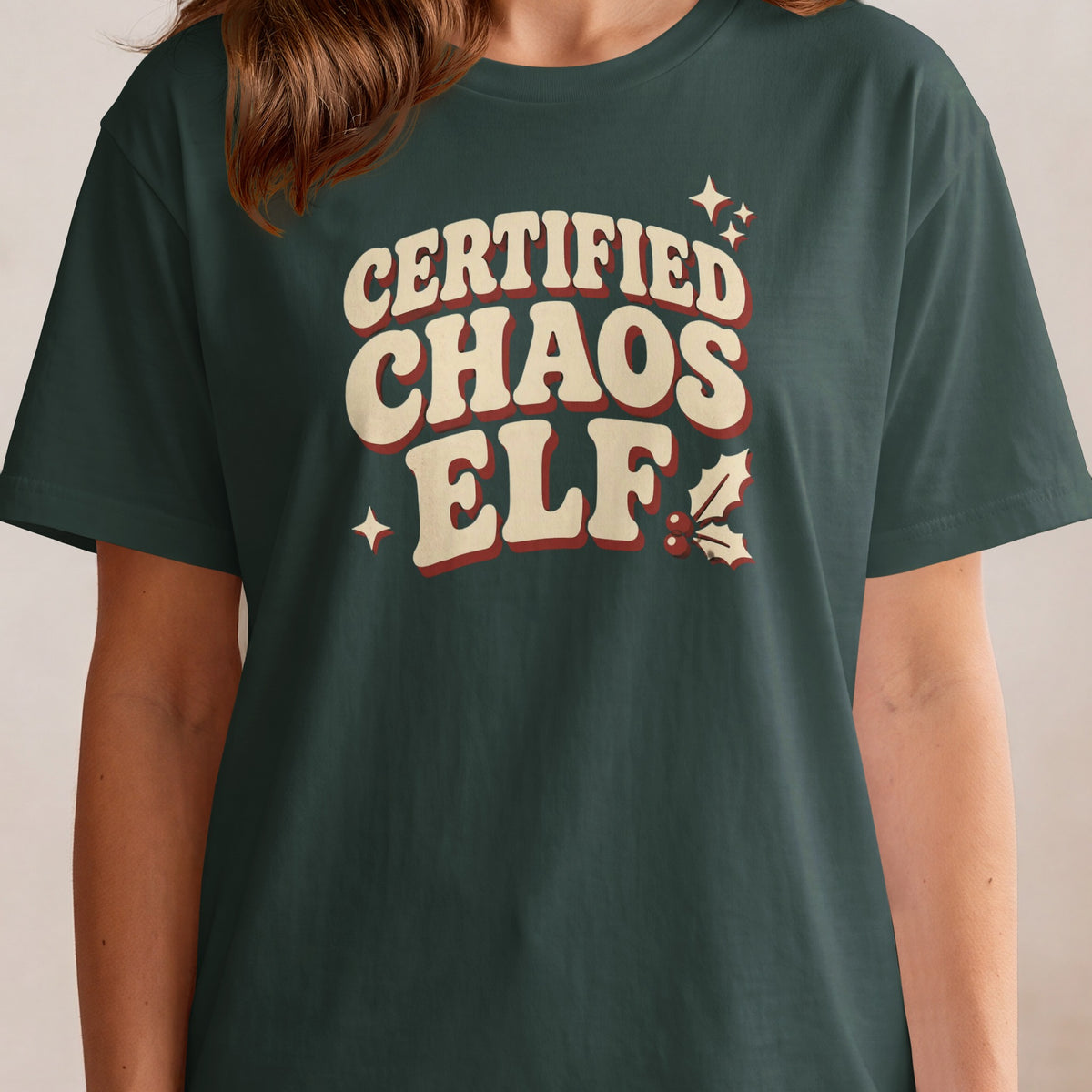 Green t-shirt with cream and red "CERTIFIED CHAOS ELF" text and Christmas graphics.