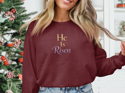 Burgundy crewneck sweatshirt with "He Is Risen" text in gold and purple.