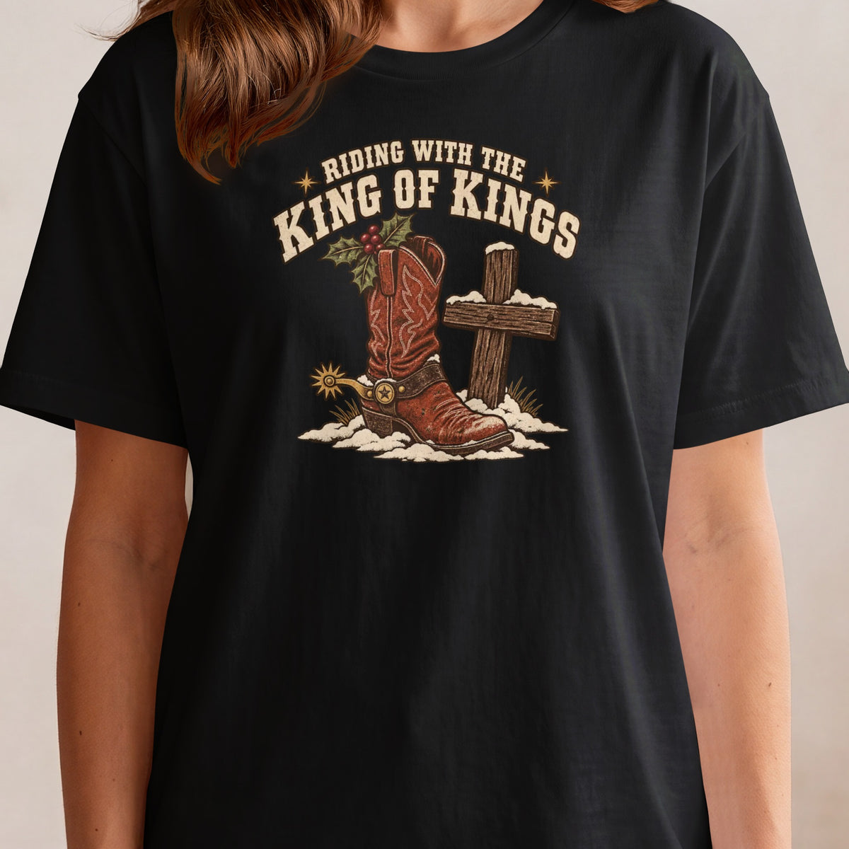 Black t-shirt graphic with cowboy boot, cross, and text: "Riding with the King of Kings".