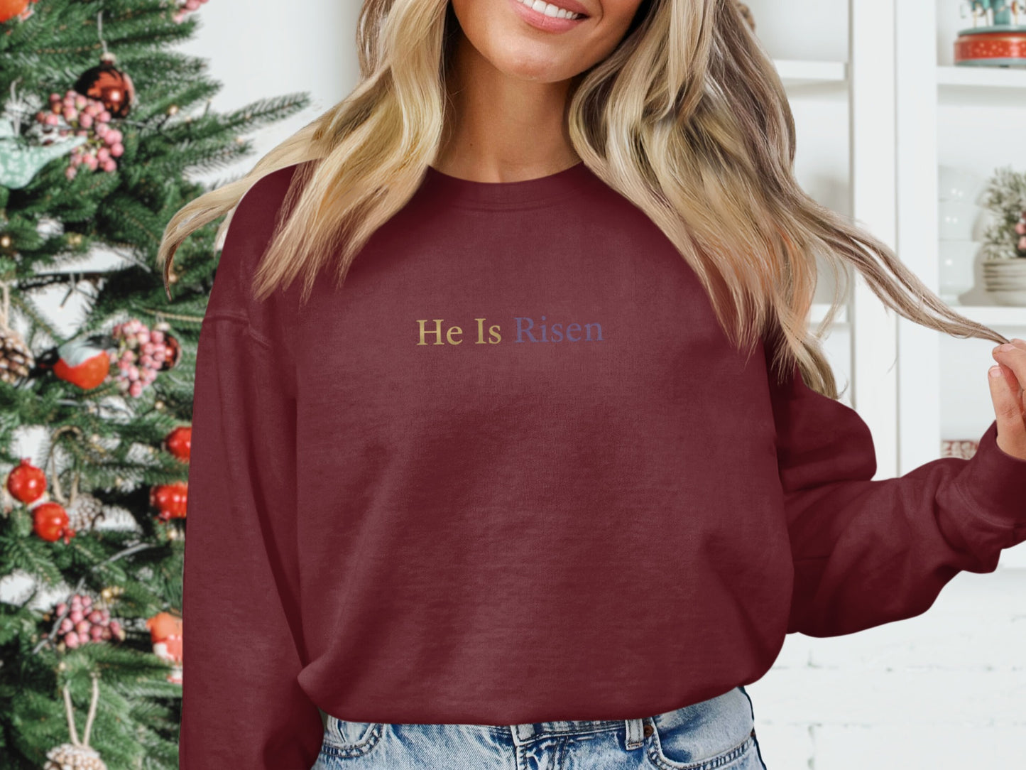 Burgundy sweatshirt with "He Is Risen" embroidered in gold and purple.
